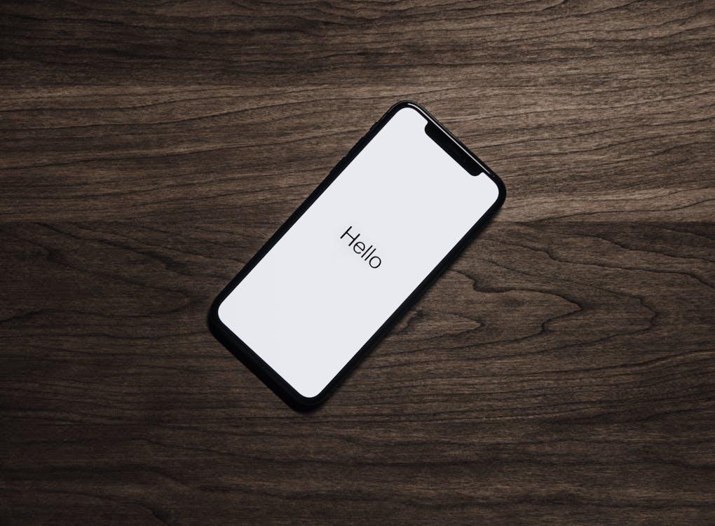 Free A smartphone displaying 'Hello' on a wooden surface, showcasing modern technology. Stock Photo